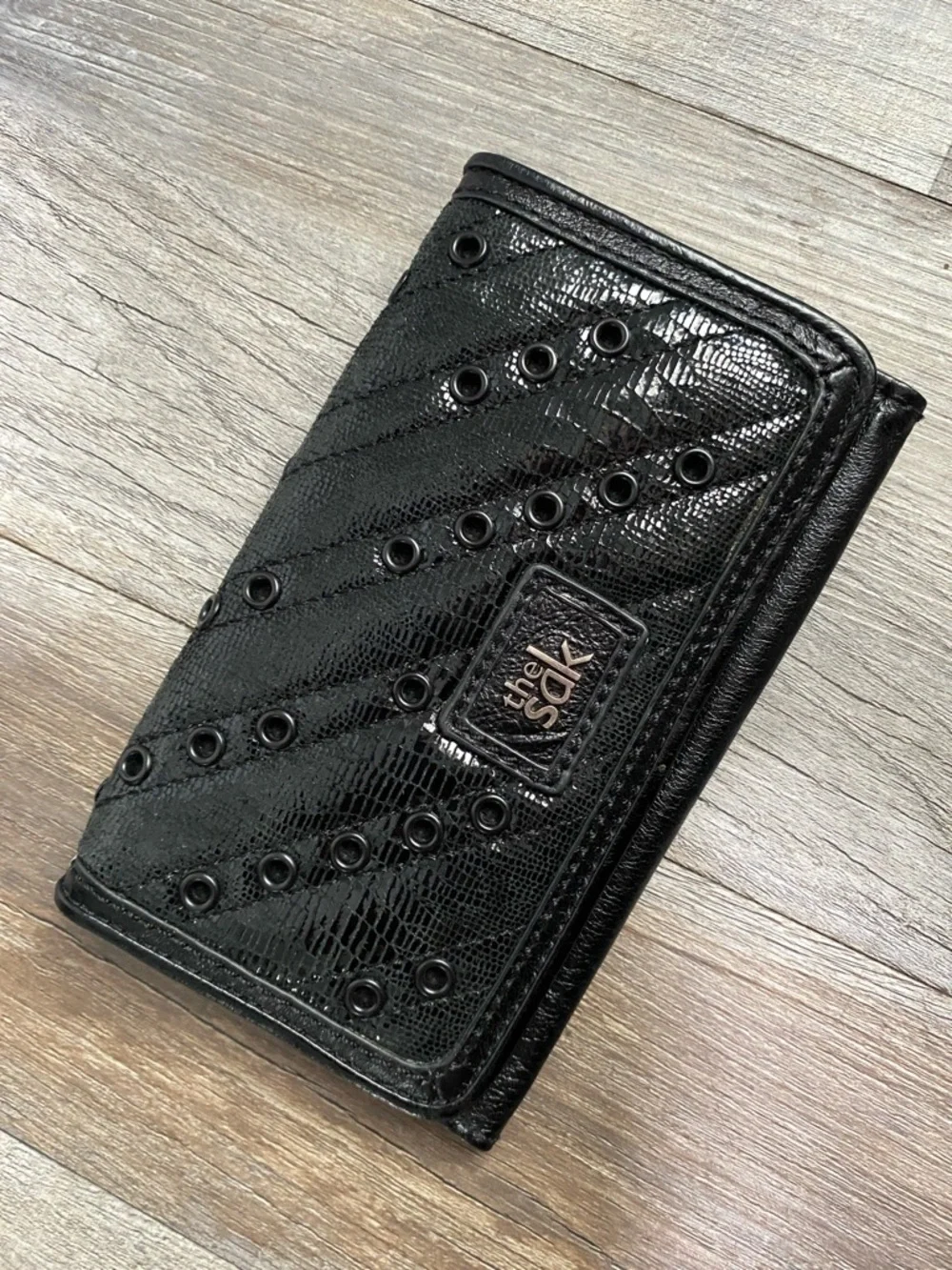 The Sak Black Quilted Eyelet Trifold Leather Wallet with Logo Plaque